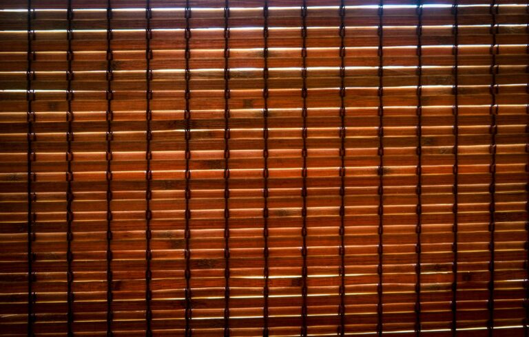 Detailed image of brown bamboo blinds with light filtering through, creating patterns.